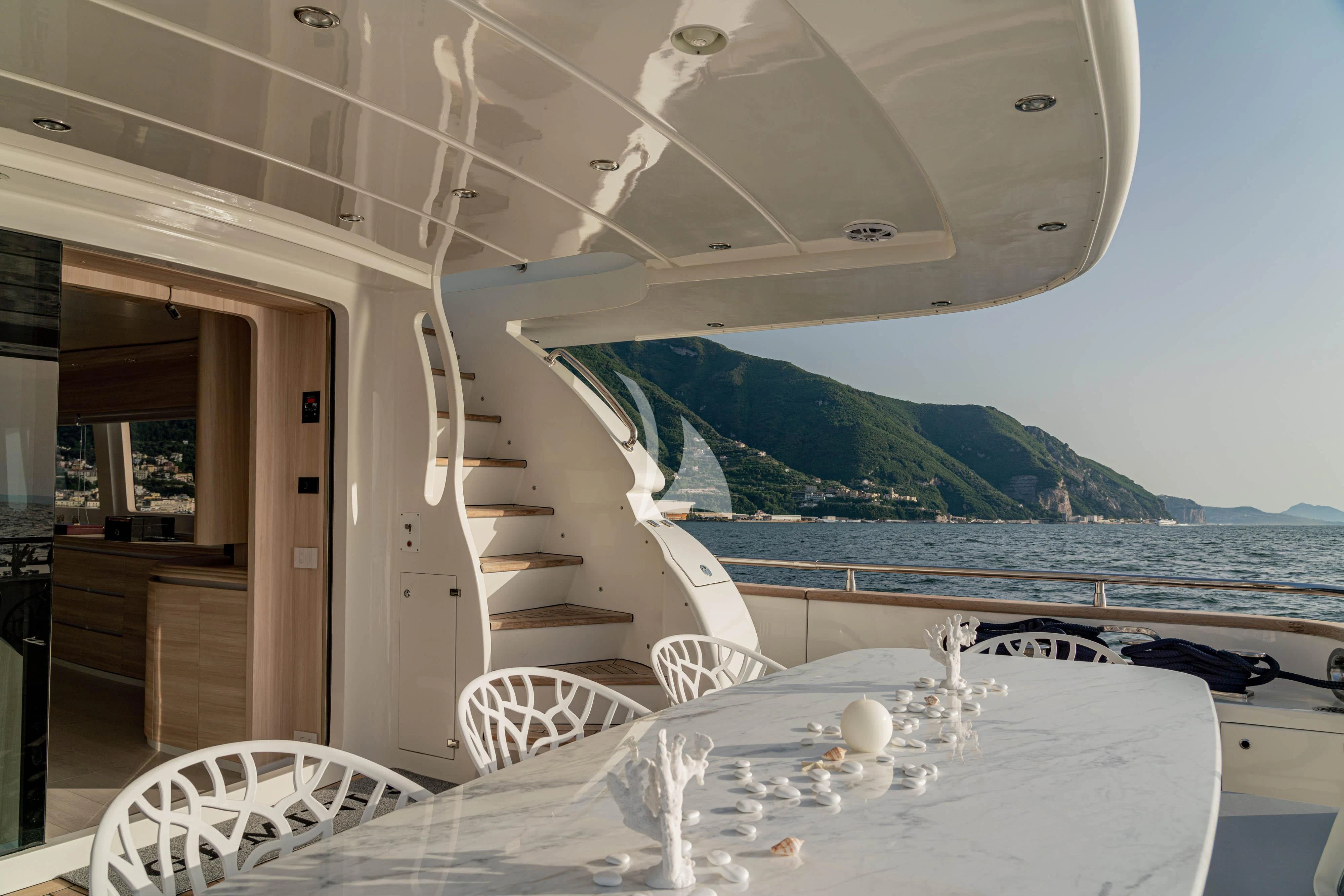 a dining table on a balcony overlooking a body of water aboard GEMINI 3 Yacht for Charter