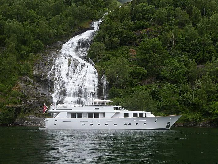 a boat on the water with Buttermilk Falls State Park in the background aboard CRISS C Yacht for Sale