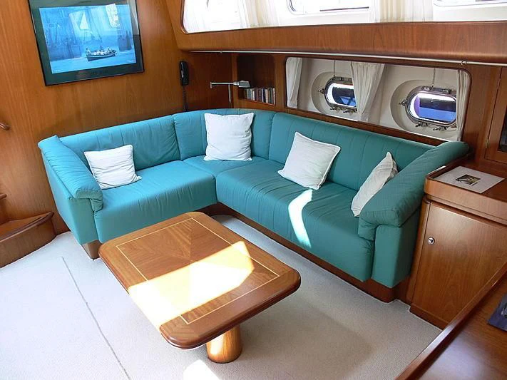 a couch with a table in a room with a mirror and a shelf aboard BLACK MOLLY Yacht for Sale