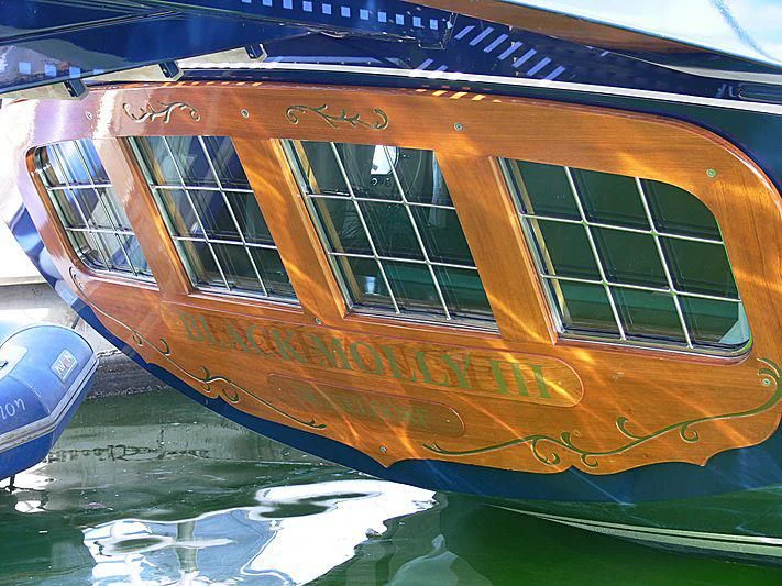 a boat with a reflection of a building on the water aboard BLACK MOLLY Yacht for Sale