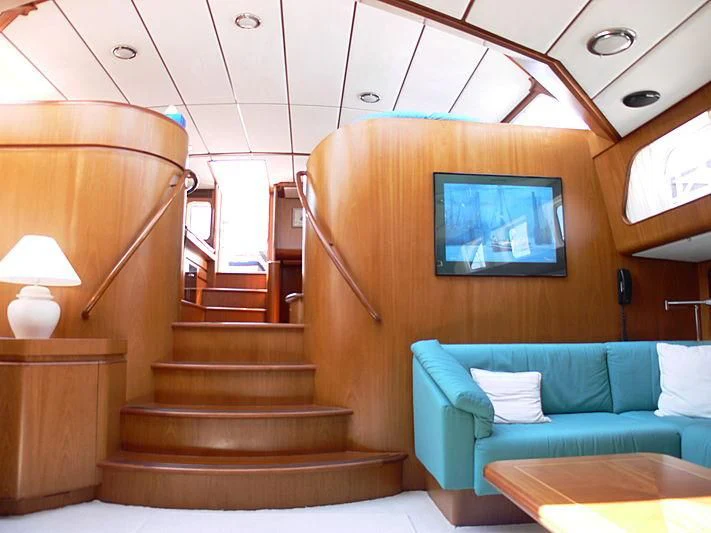 a room with a blue couch and a television aboard BLACK MOLLY Yacht for Sale