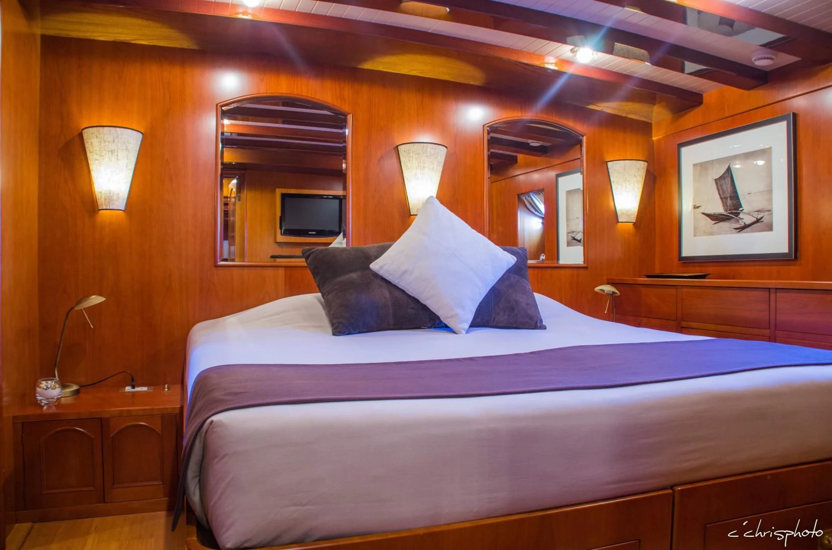 a bed with a blue and white bed spread aboard OVER THE RAINBOW OF LONDON Yacht for Charter