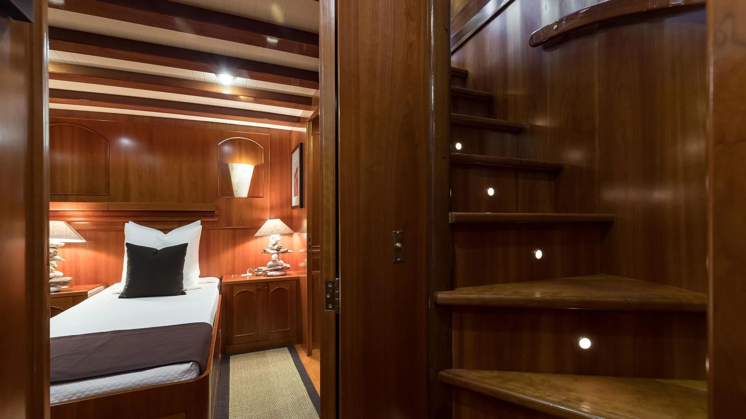 a room with a bed and a wood door aboard OVER THE RAINBOW OF LONDON Yacht for Charter
