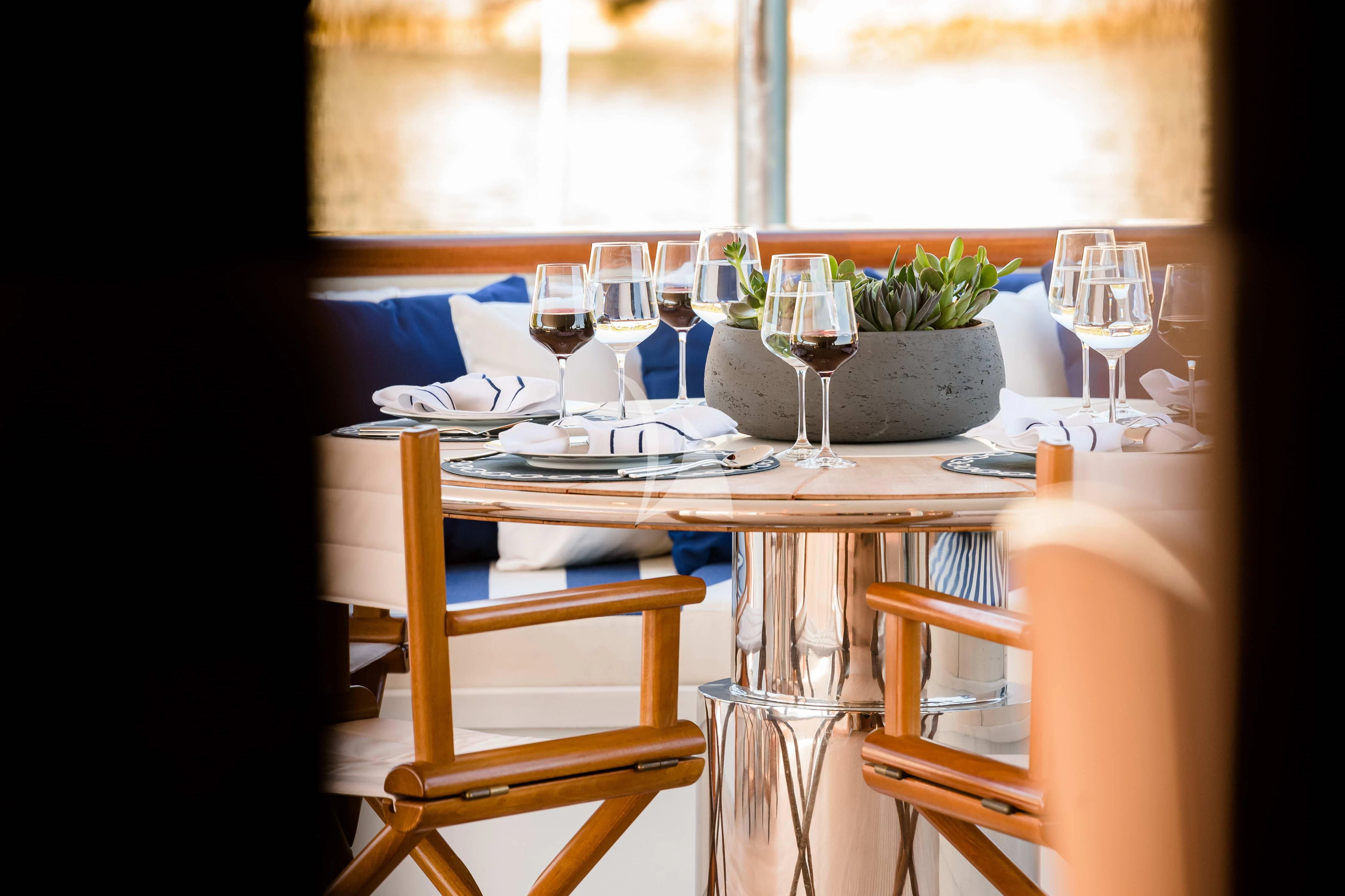 a table with wine glasses and plates on it aboard WIND OF FORTUNE Yacht for Charter