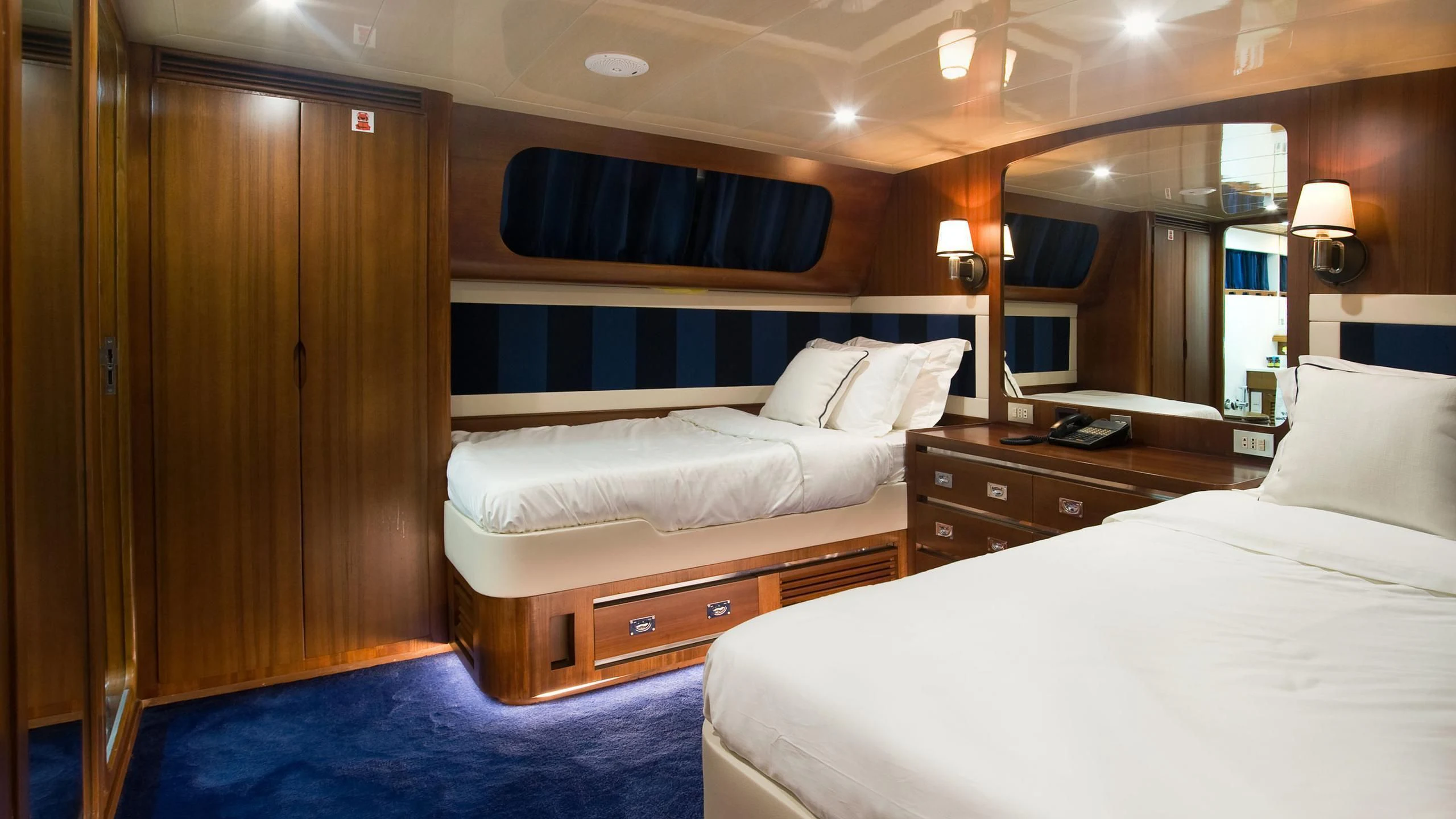 a room with beds and a dresser aboard WIND OF FORTUNE Yacht for Charter
