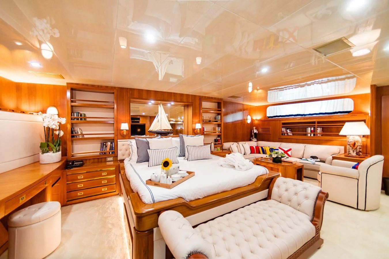 a living room with a large white couch and a bookcase aboard WIND OF FORTUNE Yacht for Charter