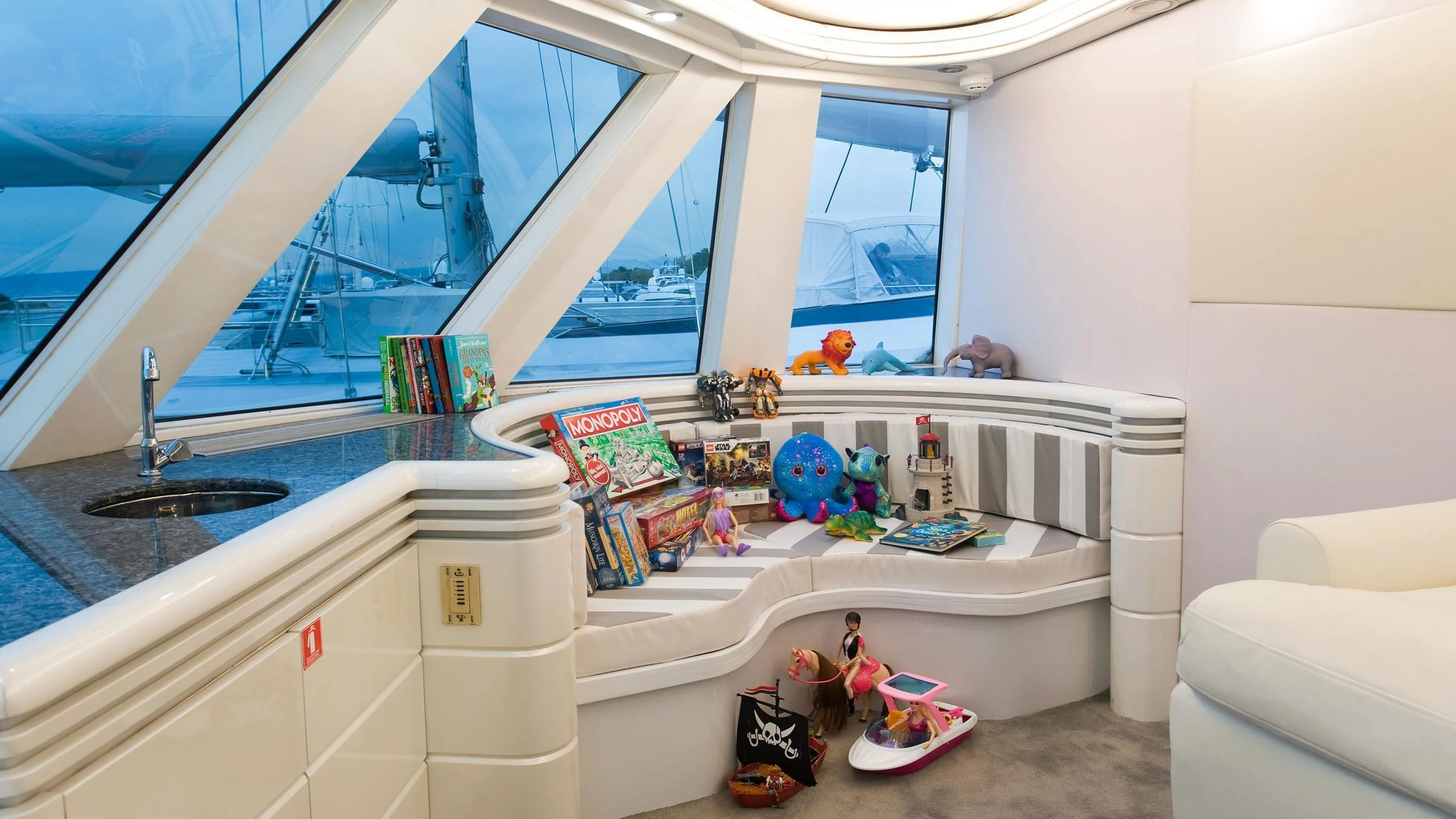 a room with a large window and a desk with toys on it aboard WIND OF FORTUNE Yacht for Charter