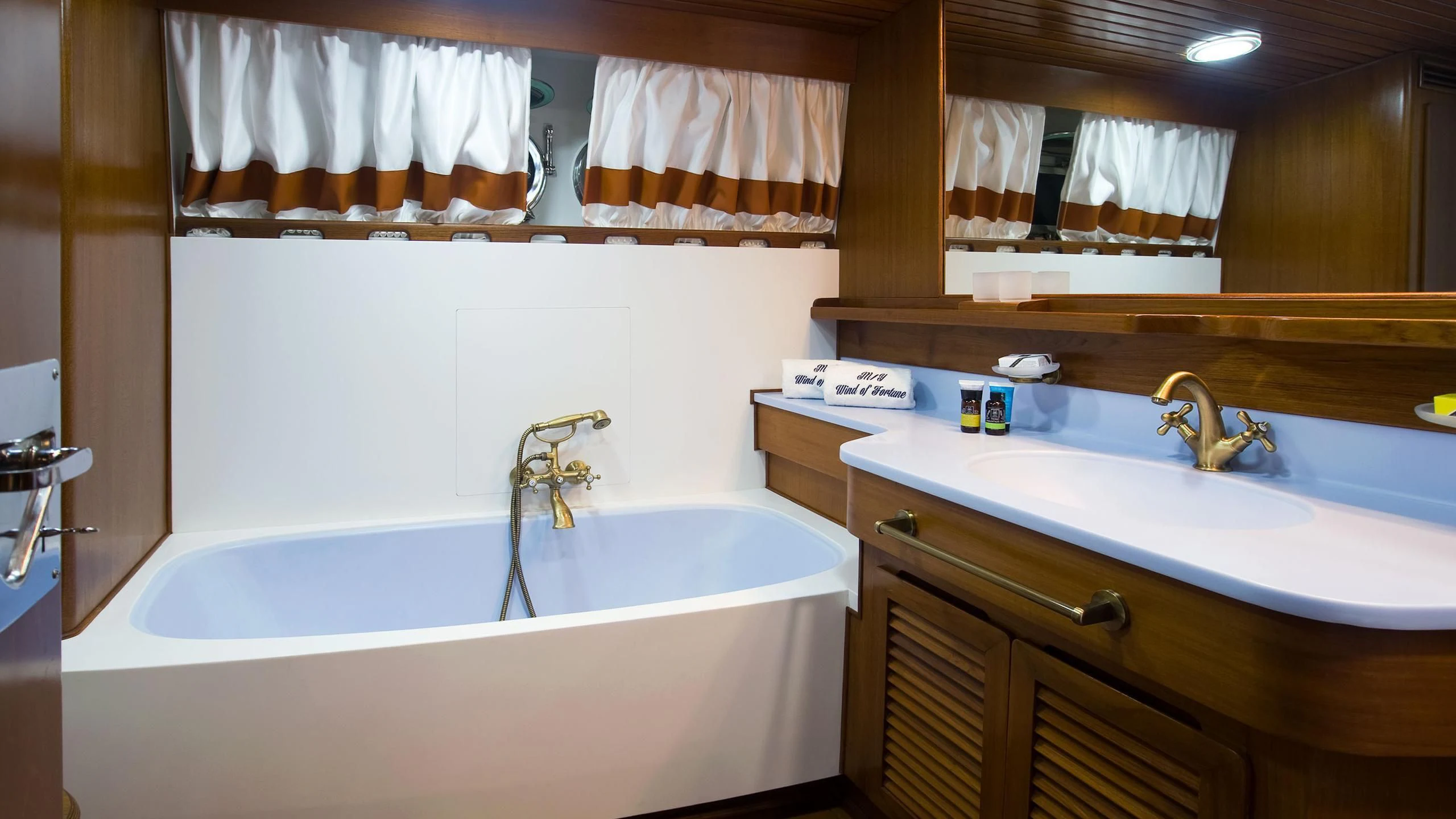 a bathroom with a tub sink and cabinets aboard WIND OF FORTUNE Yacht for Charter