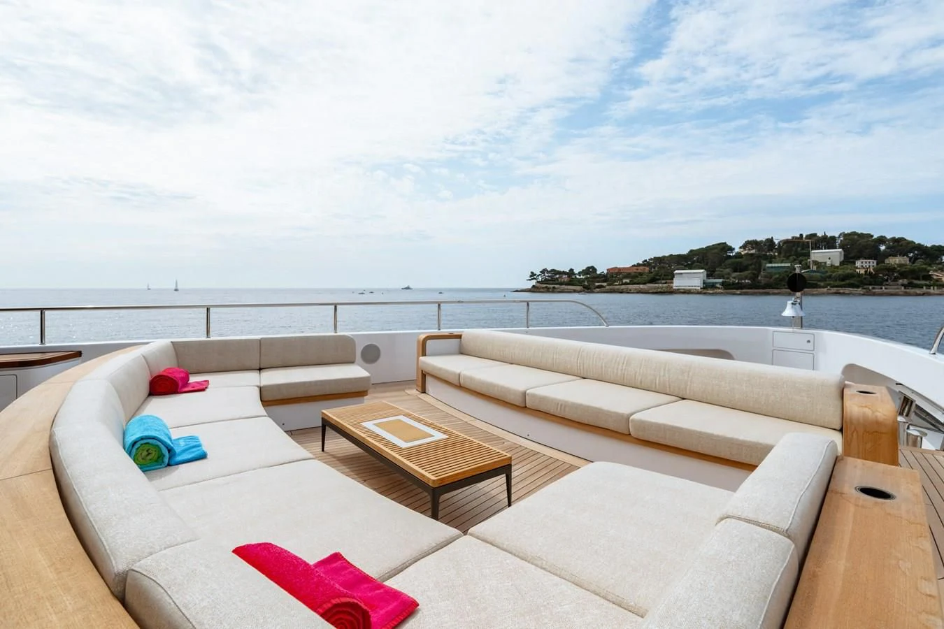 a couch and a table on a patio by a body of water aboard WAVE Yacht for Sale