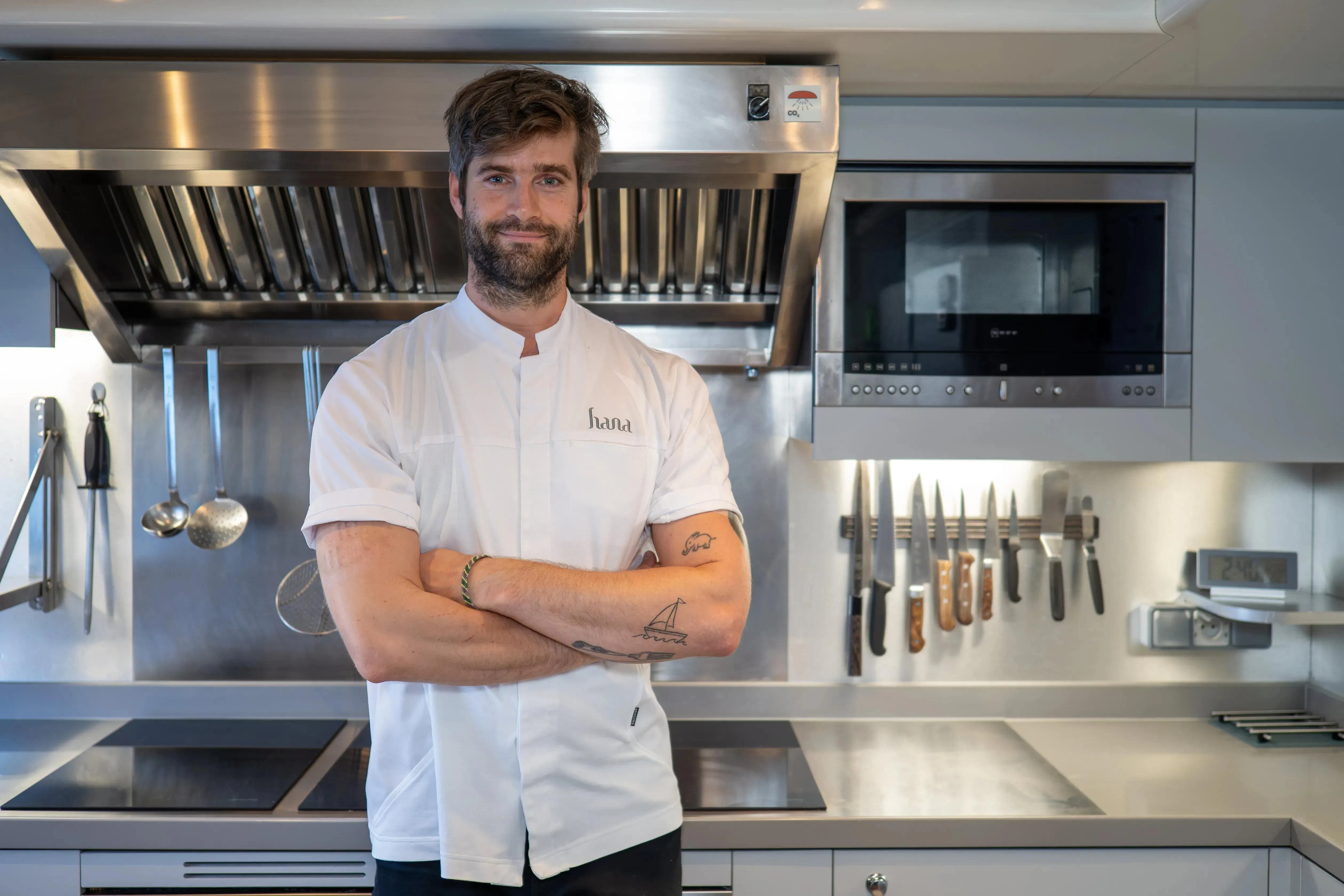 a chef standing in front of a stove aboard HANA Yacht for Charter