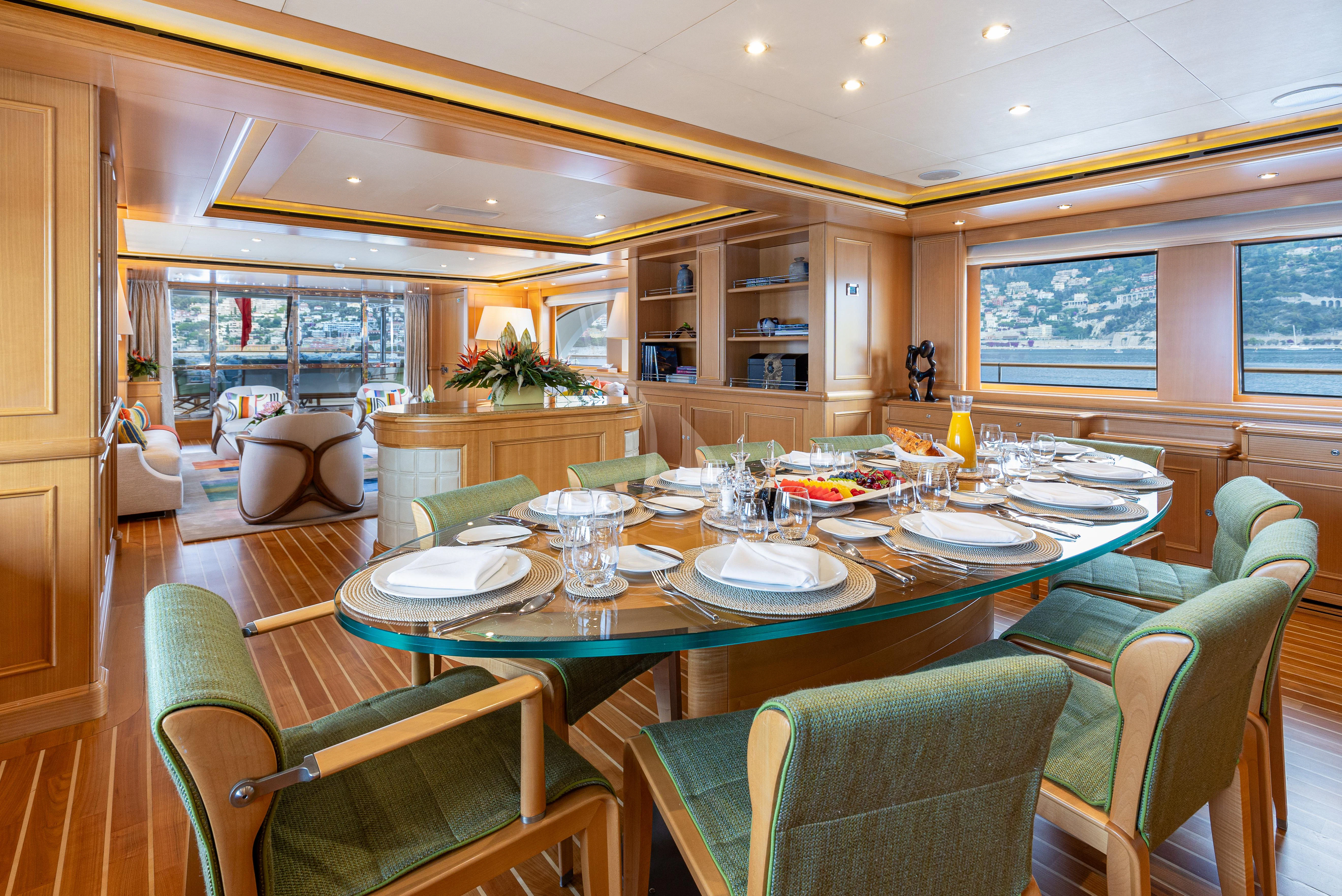a dining room with green chairs aboard HANA Yacht for Charter