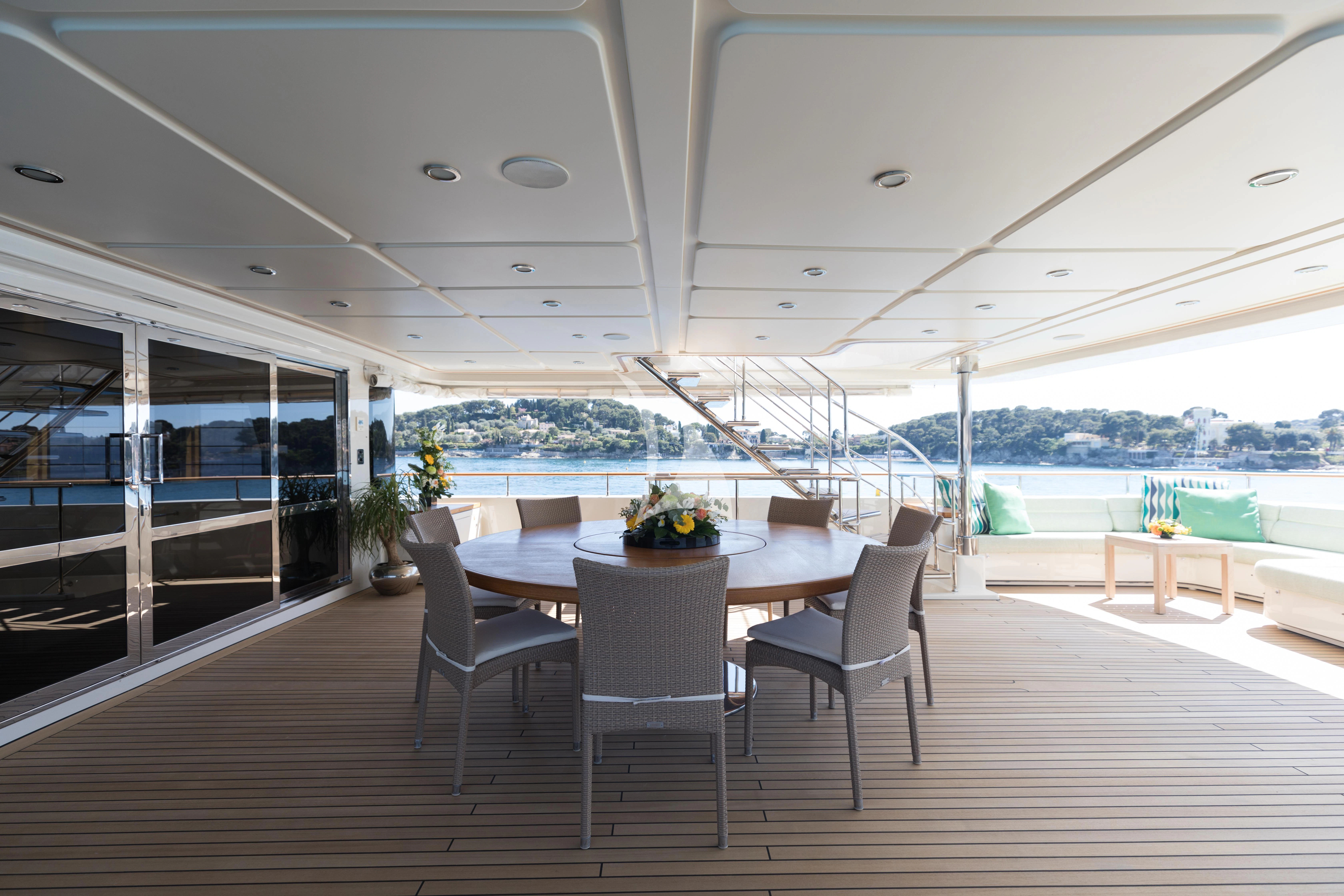 a large room with a table and chairs and a view of the water aboard HANA Yacht for Charter