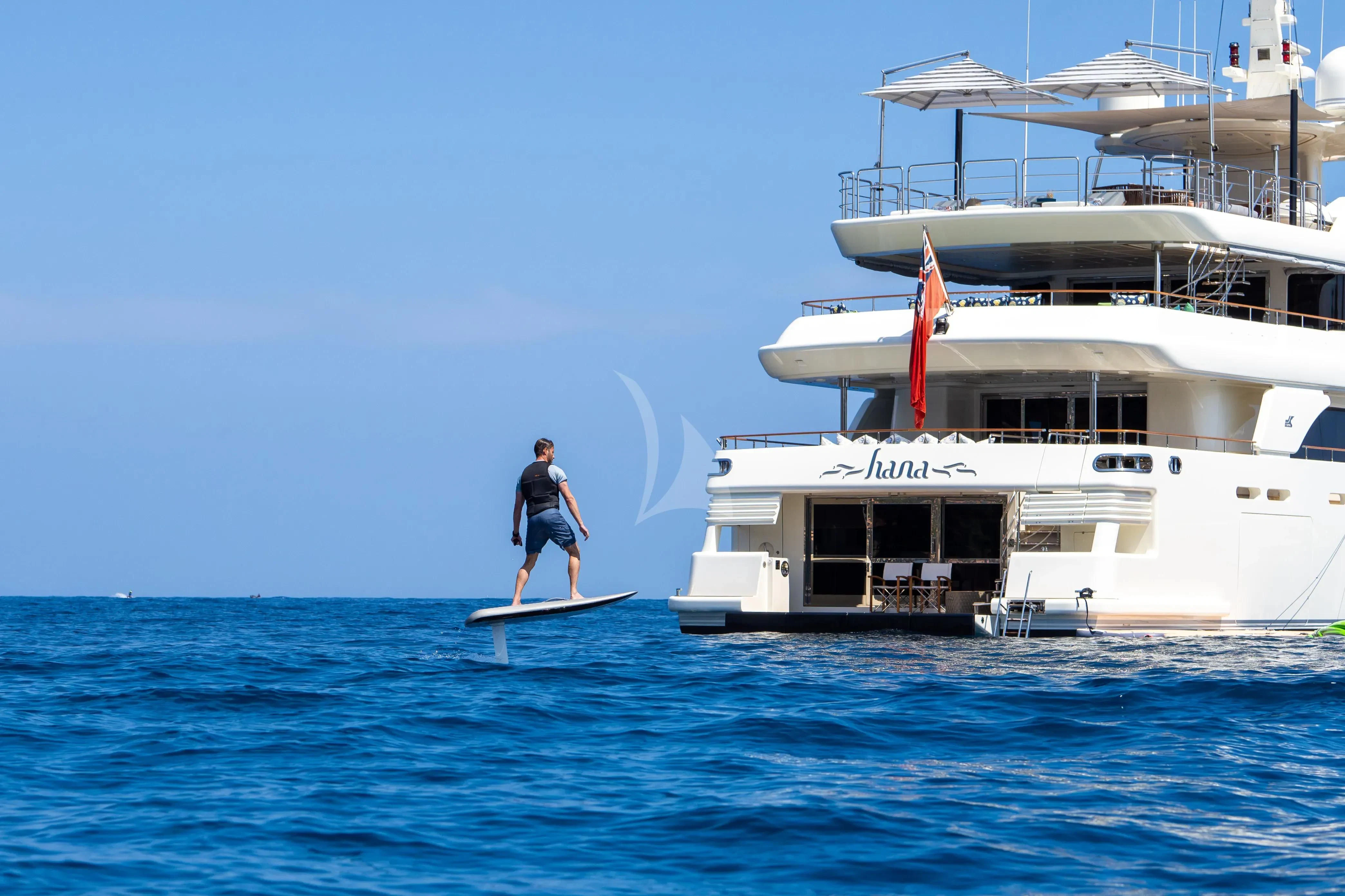 a man is surfing in the sea aboard HANA Yacht for Charter
