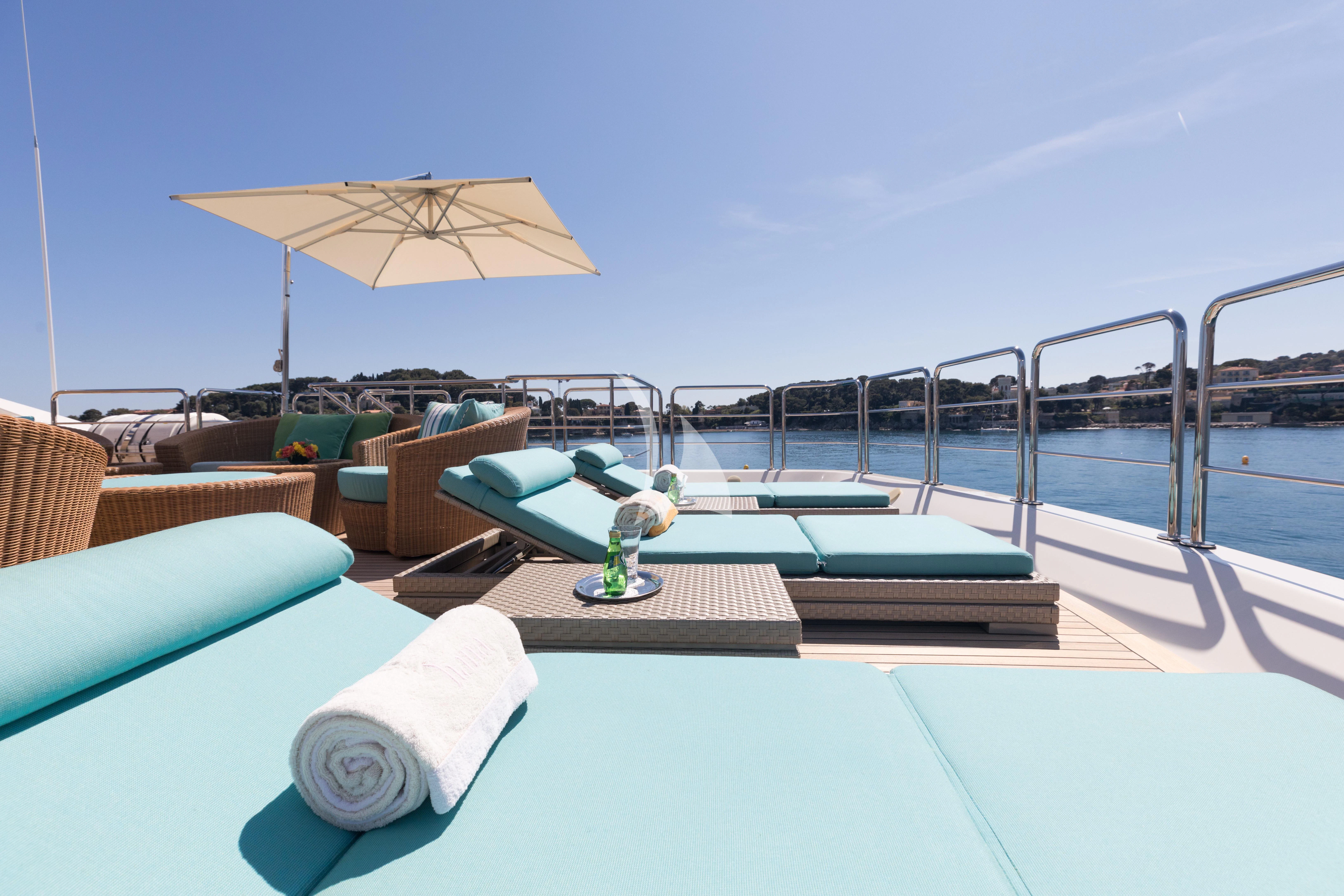 a pool table with chairs and umbrella aboard HANA Yacht for Charter