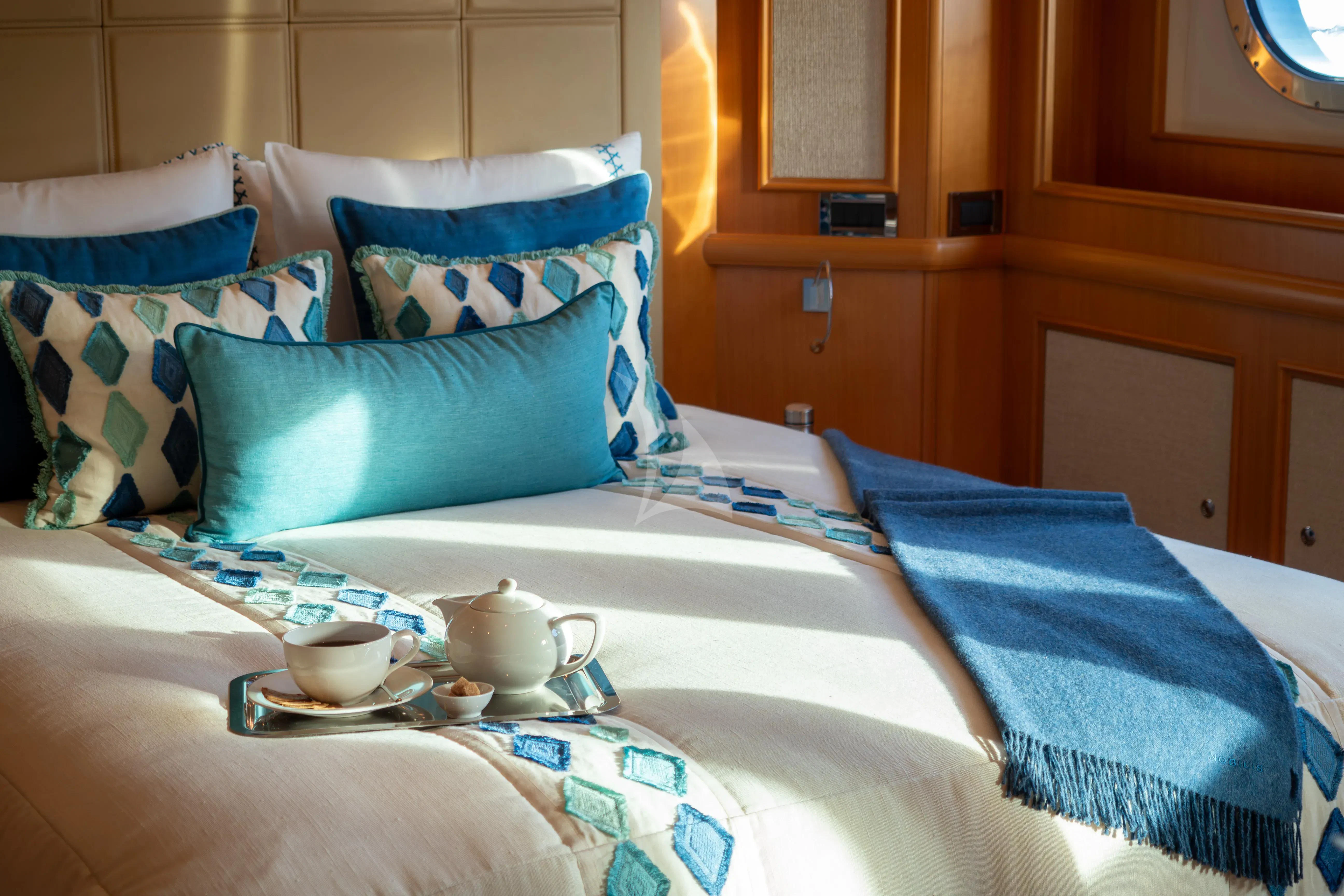 a bed with blue and white pillows aboard HANA Yacht for Charter