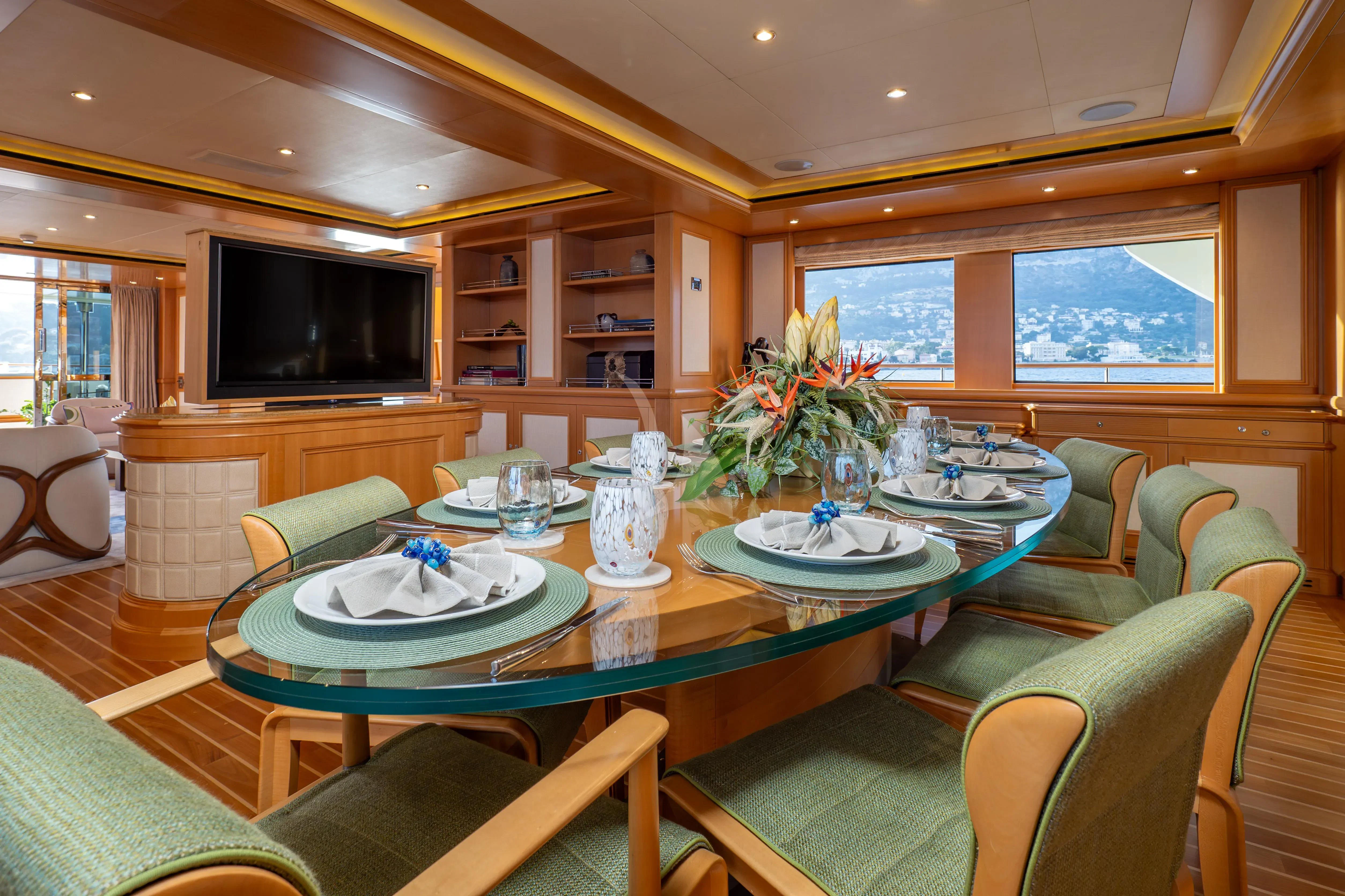 a dining room with green chairs and a table with a plant on it aboard HANA Yacht for Charter
