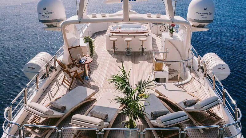 a deck with white chairs and tables on it next to a body of water aboard OAK Yacht for Charter