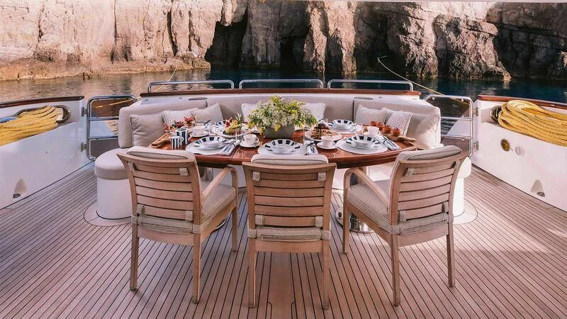 a table set with chairs and a table with food on it aboard OAK Yacht for Charter