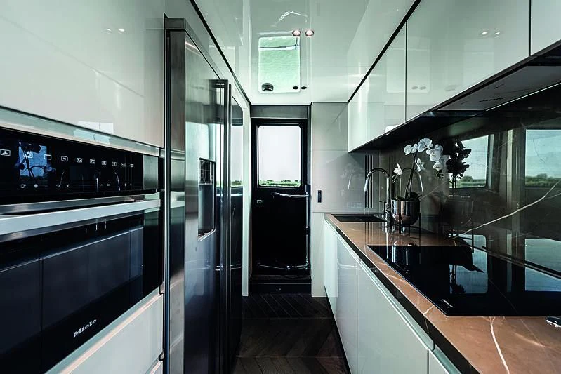 a kitchen with black appliances aboard CRANCHI SETTANTOTTO 78/01 Yacht for Sale