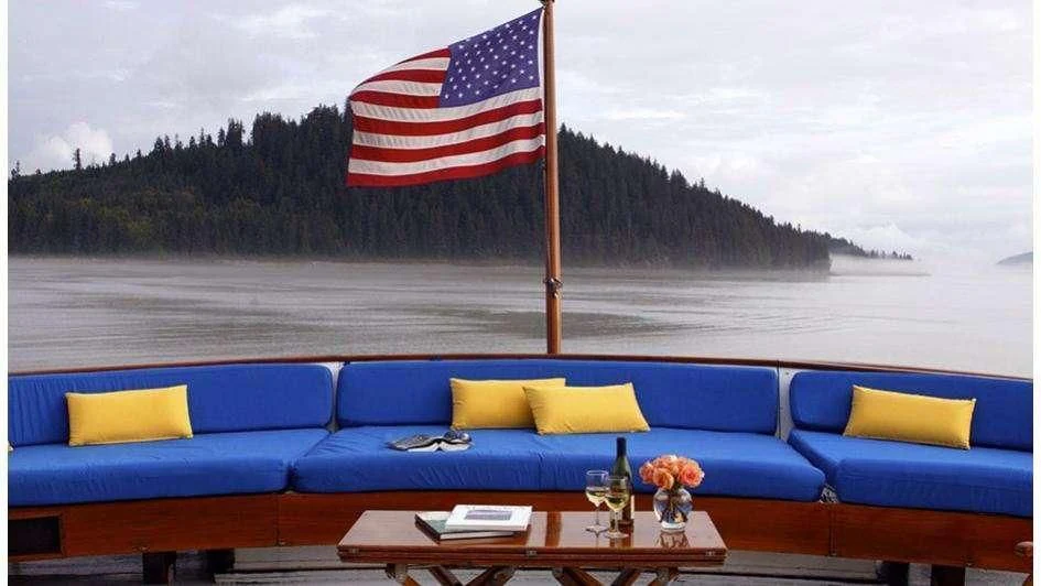 a blue couch with yellow pillows and a flag on it next to a body of water aboard STARGAZER Yacht for Sale
