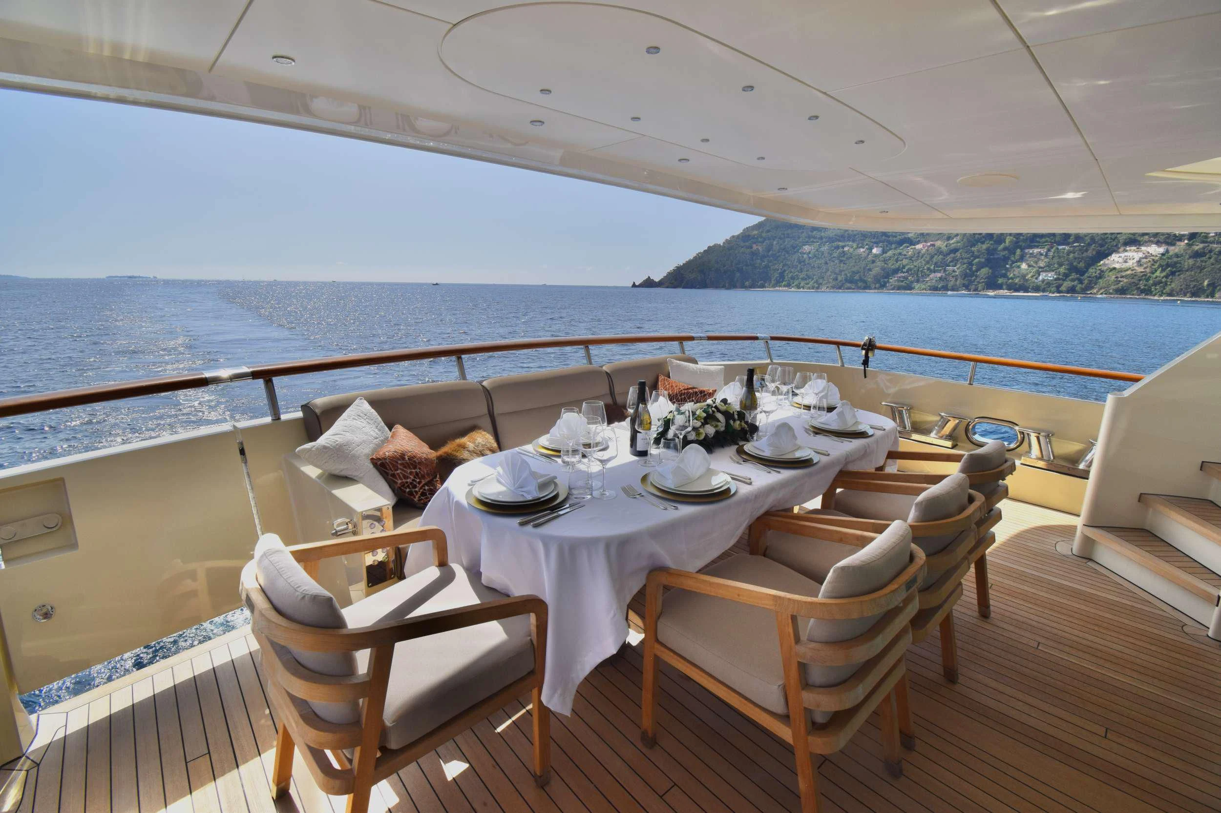 a table set for a meal on a deck overlooking the ocean aboard ORIZZONTE Yacht for Sale