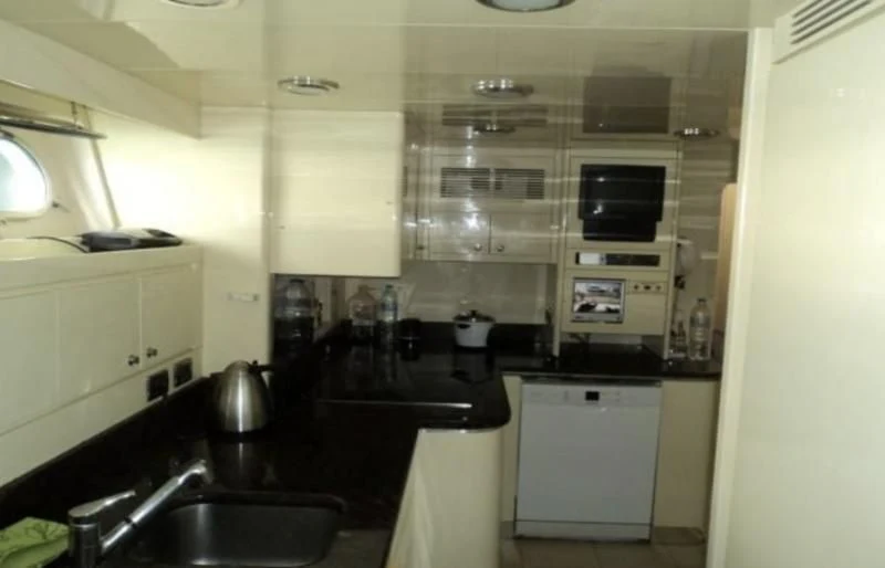 a small kitchen with white cabinets aboard ELMAR Yacht for Sale