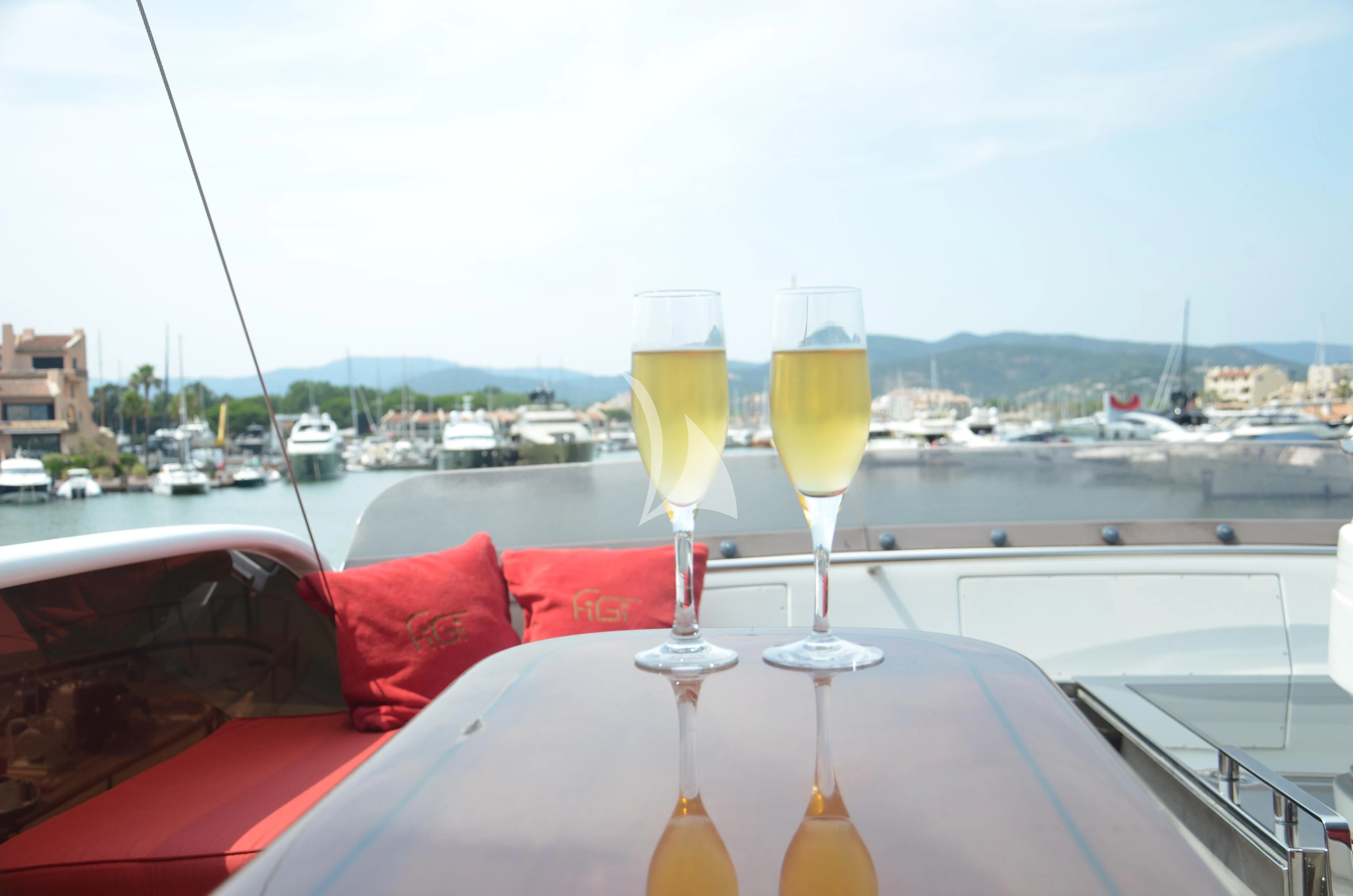 a couple of glasses of wine on a table with boats in the background aboard FIGI Yacht for Sale