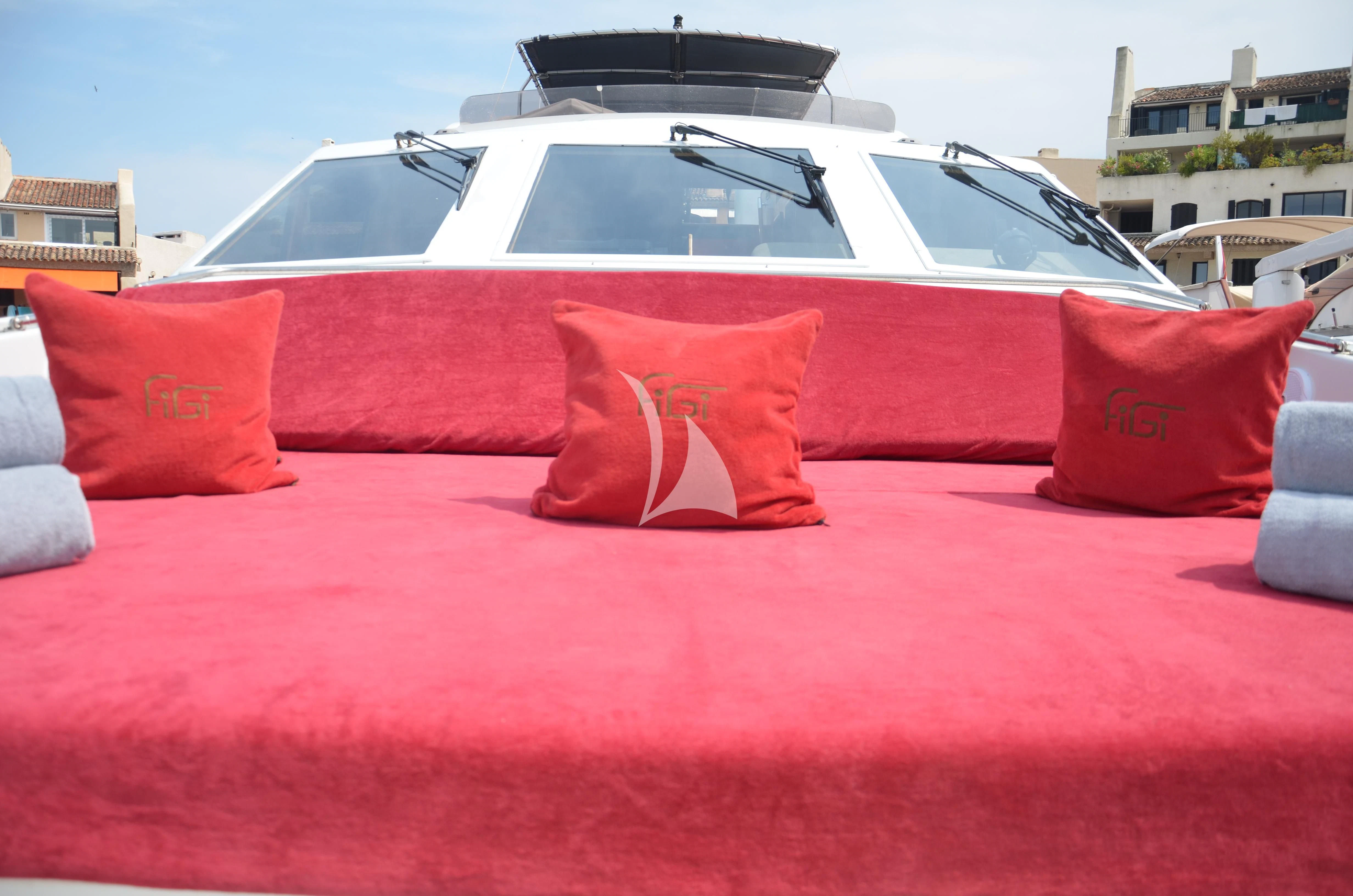 a red couch with pillows and a white car in the background aboard FIGI Yacht for Sale