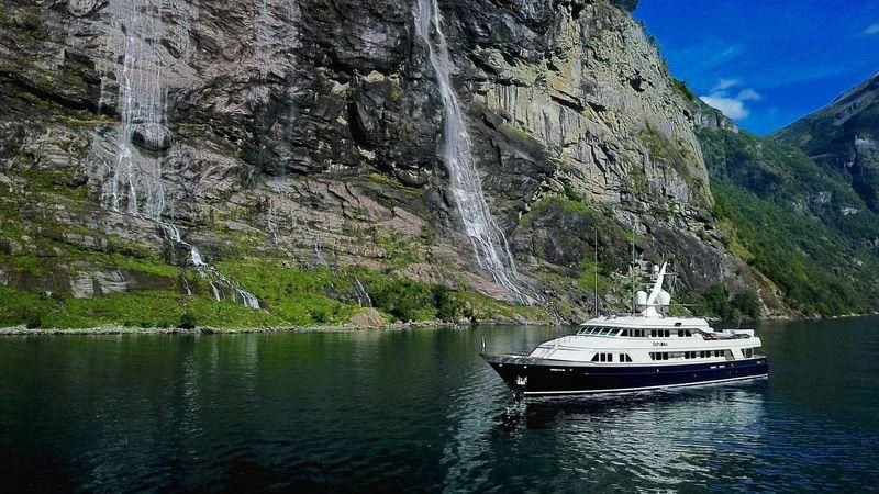 a boat in the water by a waterfall aboard EXPLORA Yacht for Sale