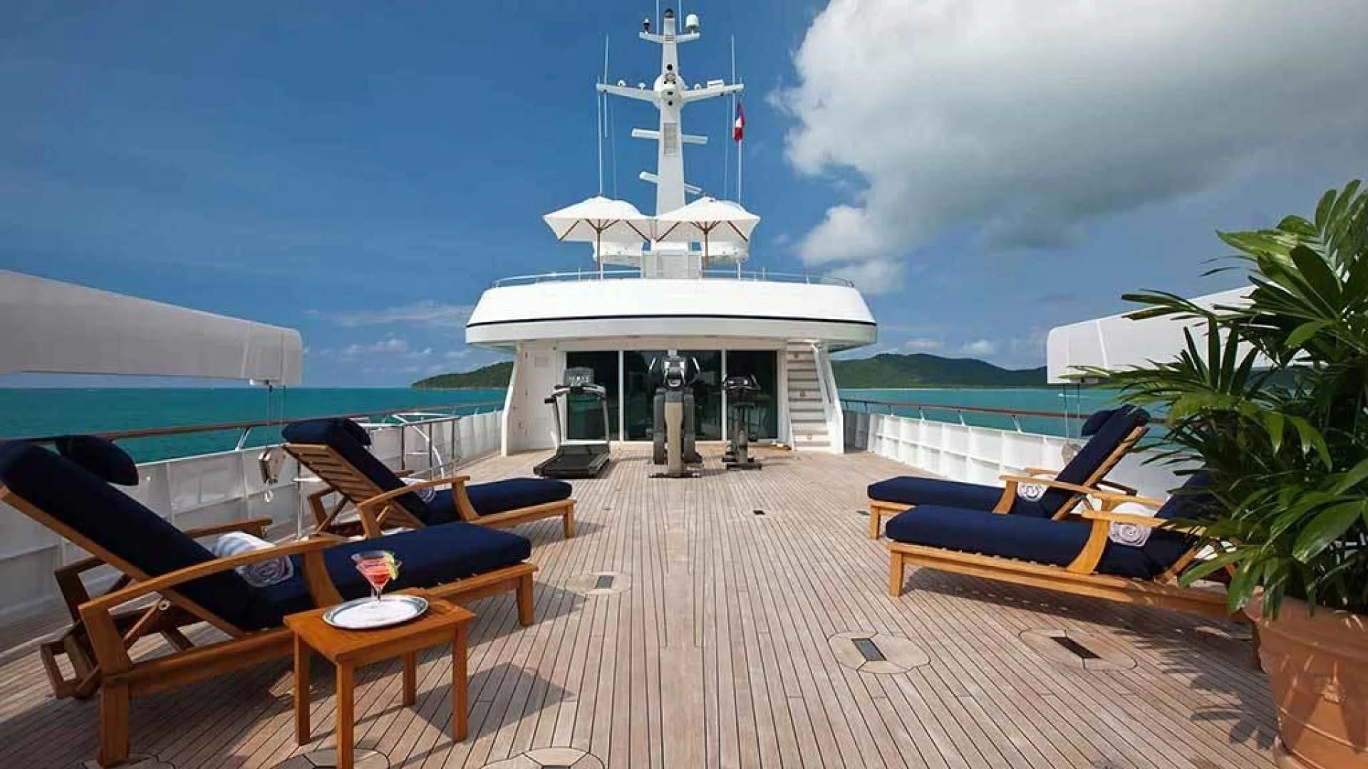 a deck with a table chairs and a boat on it aboard EXPLORA Yacht for Sale