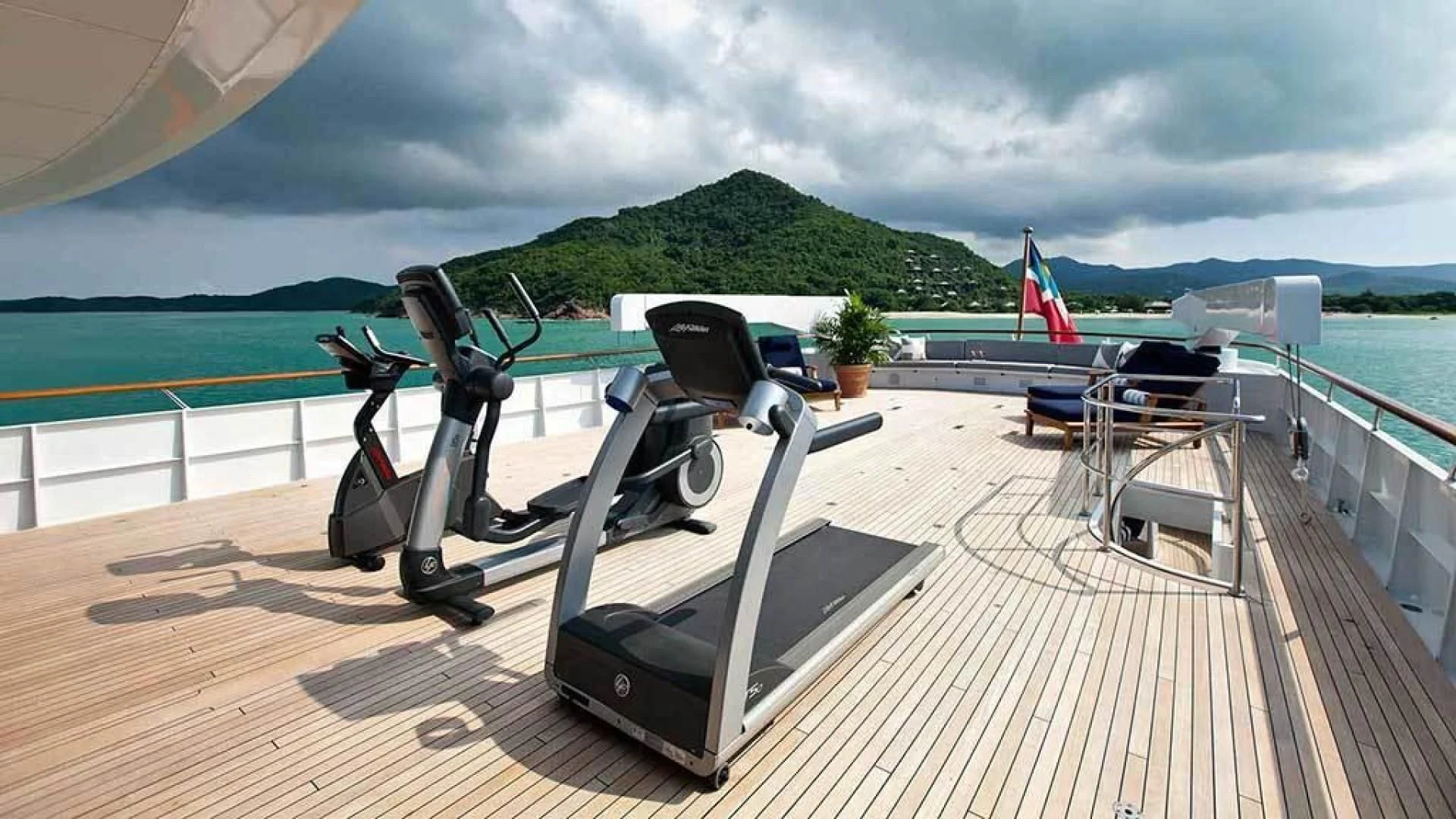 a deck with a large pool and a large deck with chairs and a flag on it aboard EXPLORA Yacht for Sale