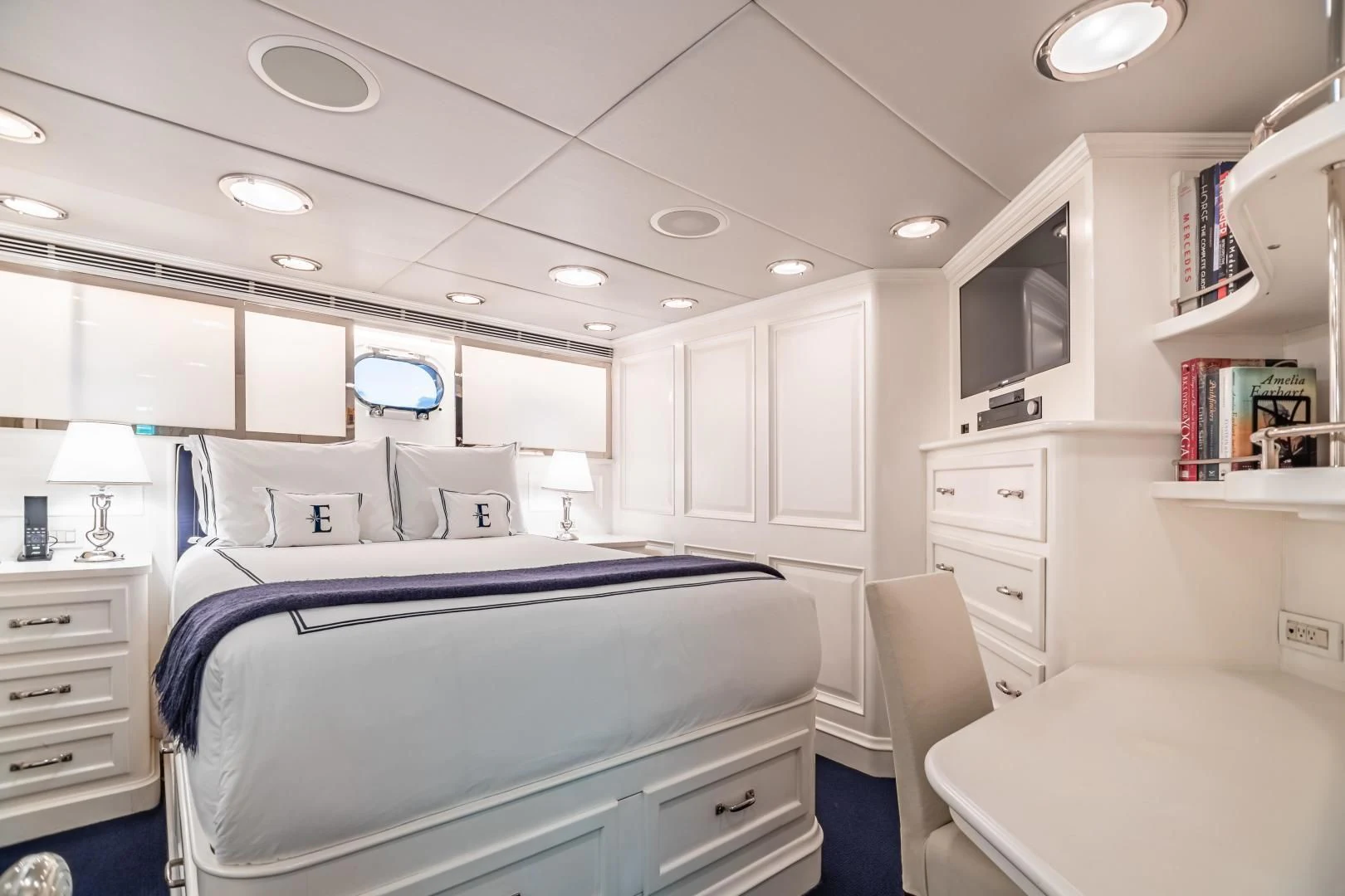 a bedroom with a bed and a desk aboard EXPLORA Yacht for Sale