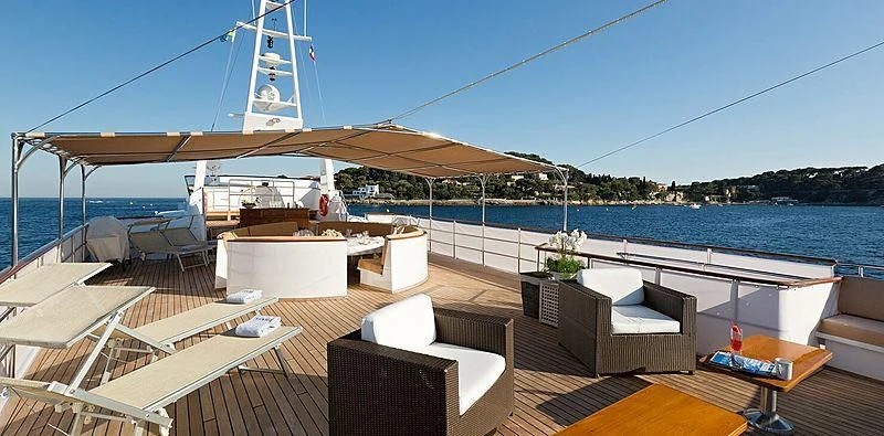 a deck with a view of the ocean and a boat aboard SHAHA Yacht for Sale