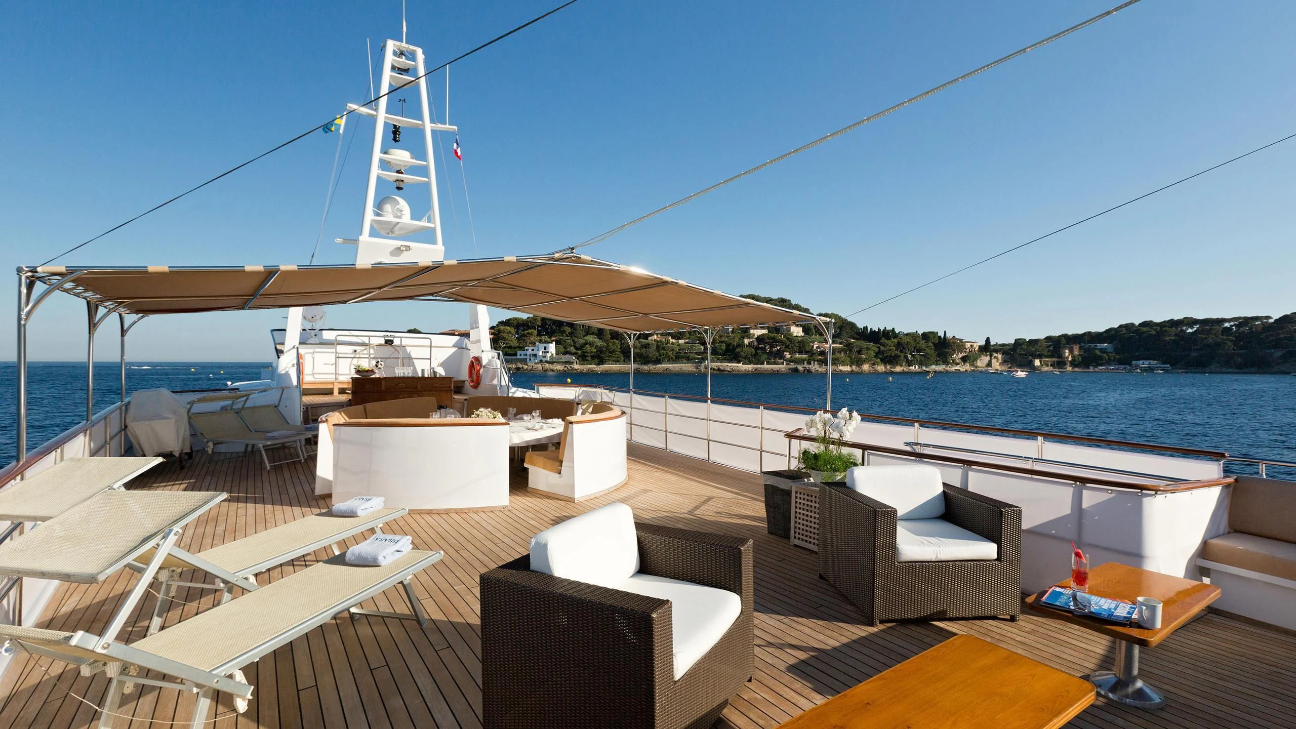 a deck with a view of a large body of water and a large ship in the background aboard SHAHA Yacht for Sale