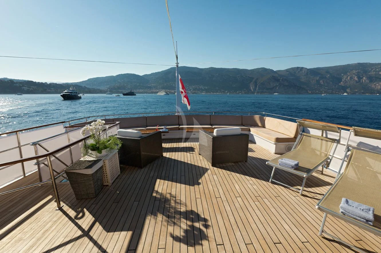 a deck with chairs and a flag on it aboard SHAHA Yacht for Sale