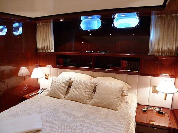 a bed with pillows and a television above it aboard ARGO B Yacht for Sale