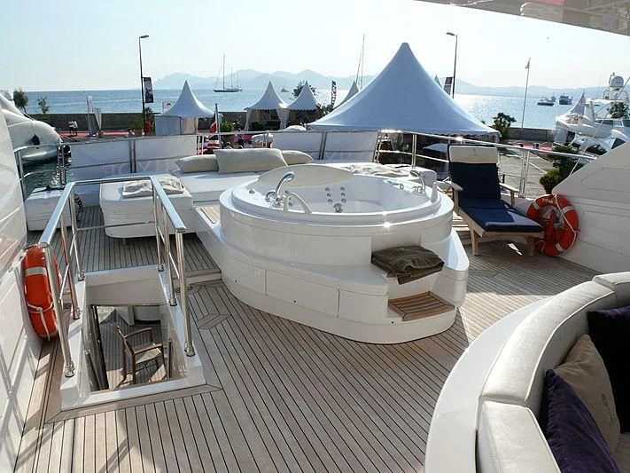 a deck with a chair and a table with a tent and boats on it aboard ARGO B Yacht for Sale