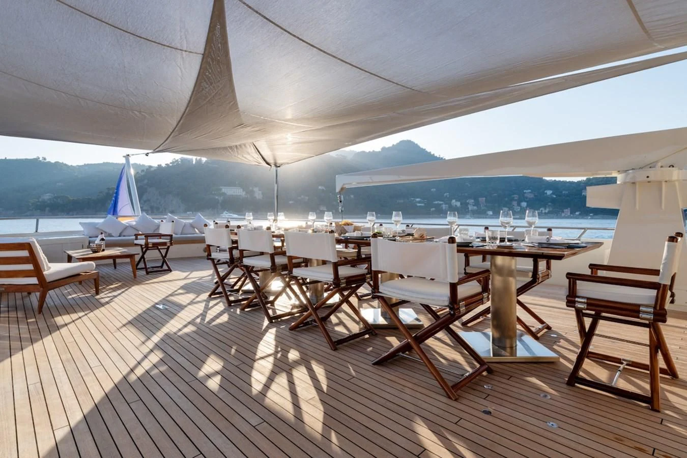 a room with a table chairs and a sailboat on the water aboard BG Yacht for Sale