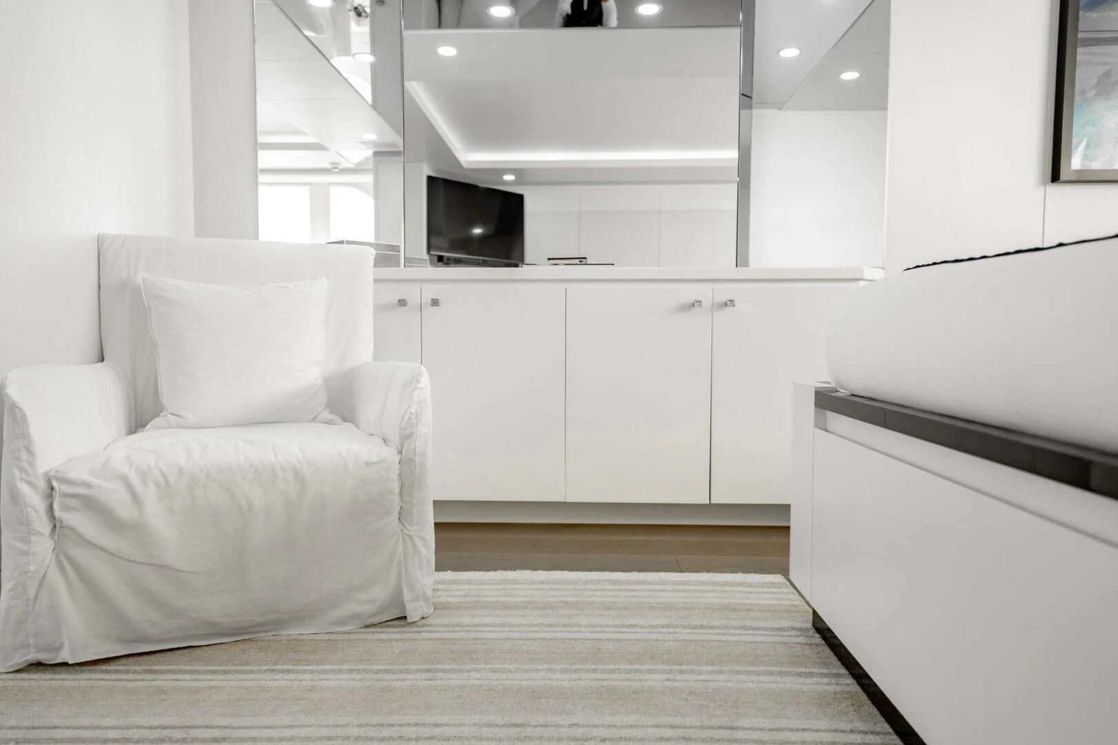 a white living room with a wood floor and white cabinets aboard BG Yacht for Sale