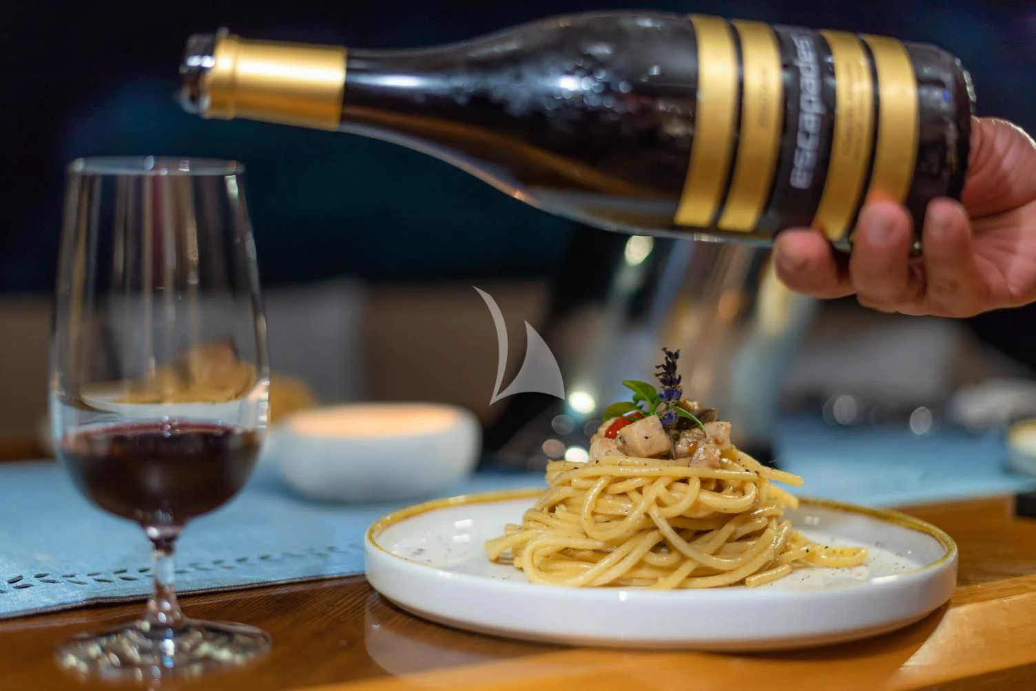 a bottle of wine pouring a glass of wine aboard STELA 117 Yacht for Sale