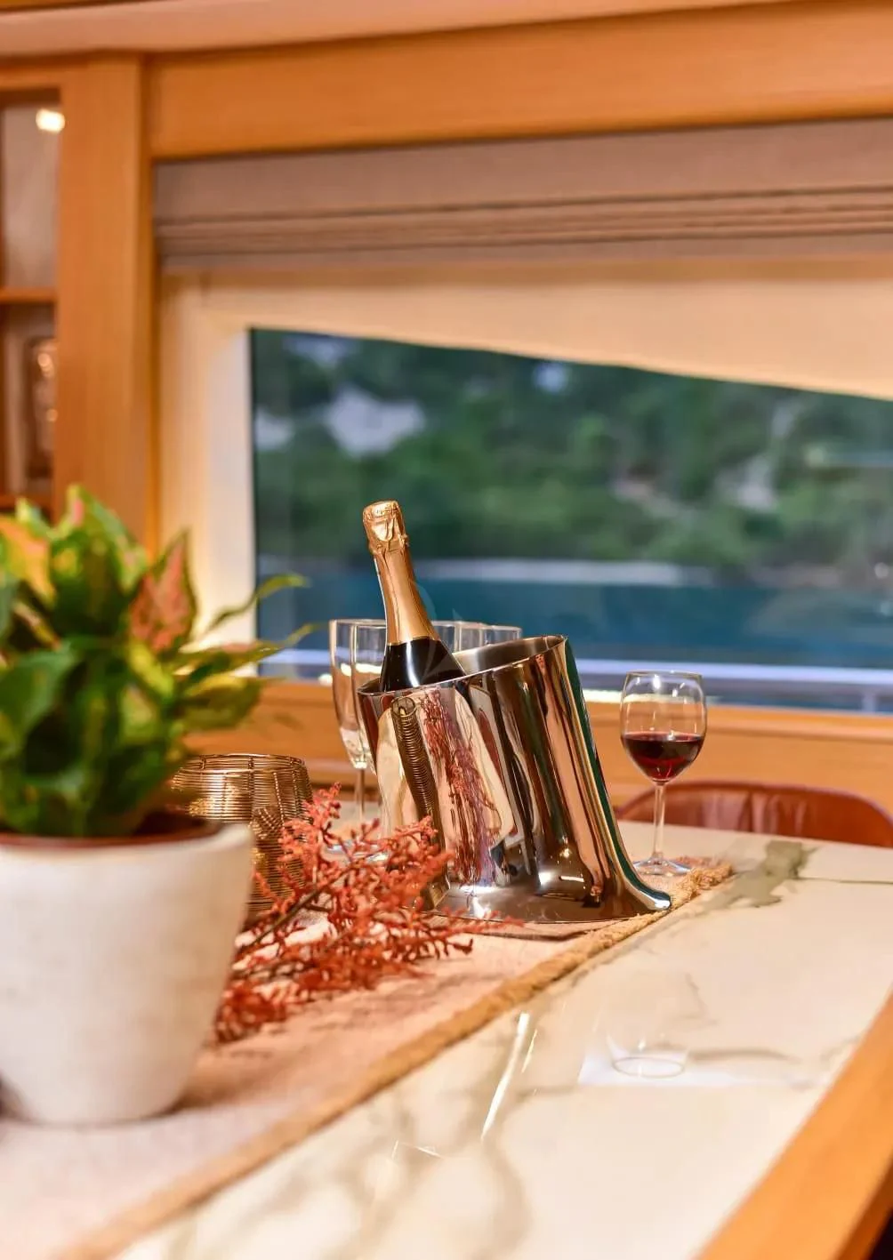 a table with glasses and a bottle of wine aboard STELA 117 Yacht for Sale