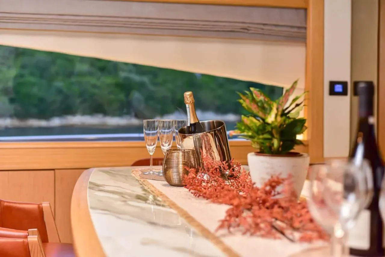 a table with wine glasses and a plant on it aboard STELA 117 Yacht for Sale
