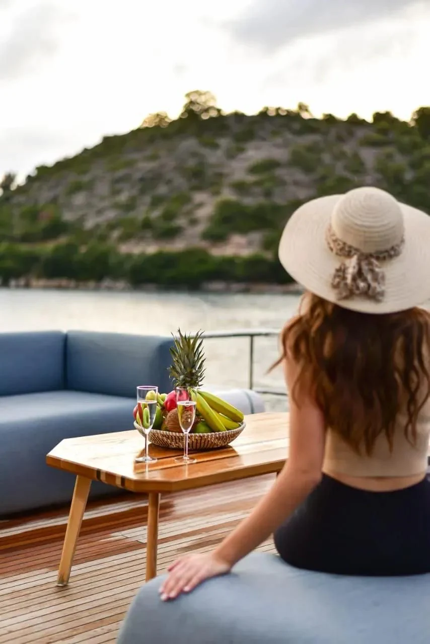 a person sitting at a table with a basket of fruit on it aboard STELA 117 Yacht for Sale