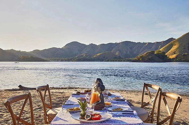 a couple of people sitting at a table with food on it by the water aboard MISCHIEF Yacht for Sale