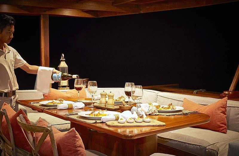 a person sitting at a table with food and wine glasses aboard MISCHIEF Yacht for Sale