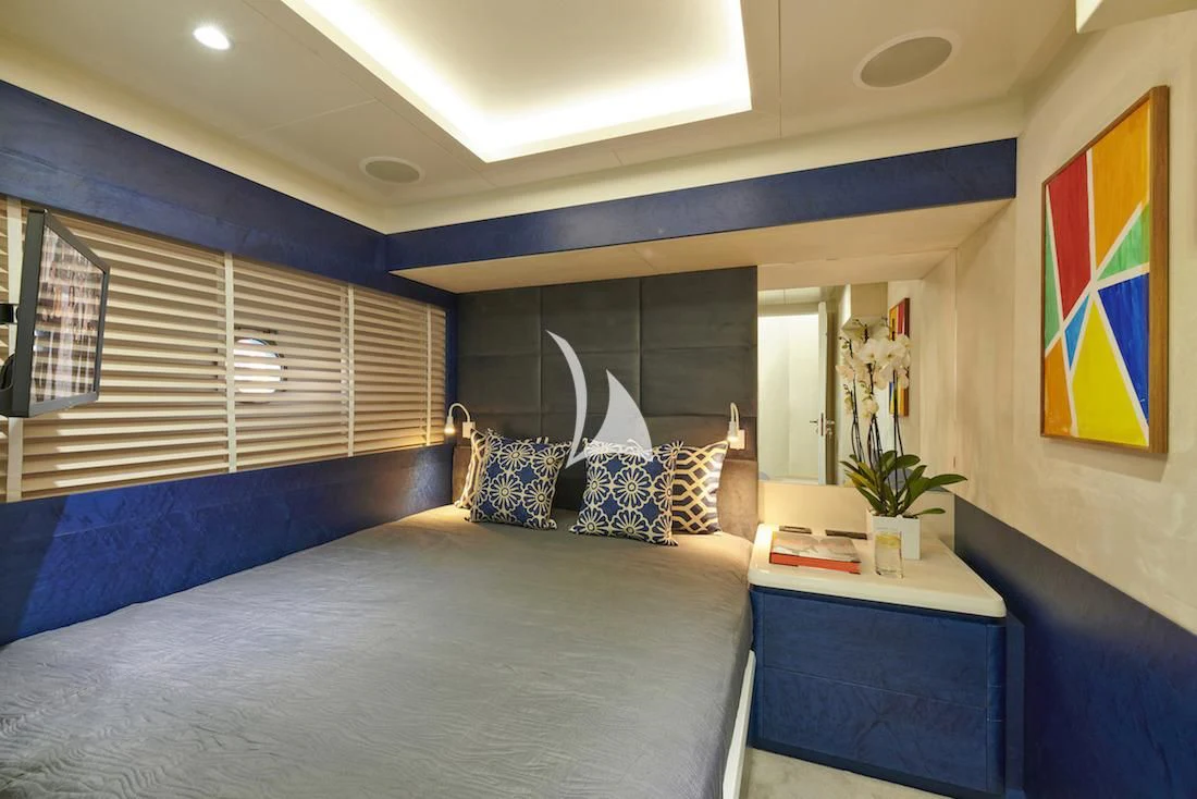 a bedroom with a blue bed and a blue table with a white table aboard LA FENICE Yacht for Charter