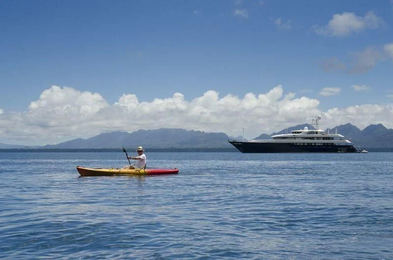 a person on a boat with a paddle and a boat in the water aboard ARCHIMEDES Yacht for Sale