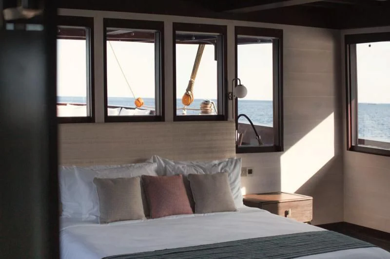 a bed with pillows and a window aboard VELA Yacht for Charter