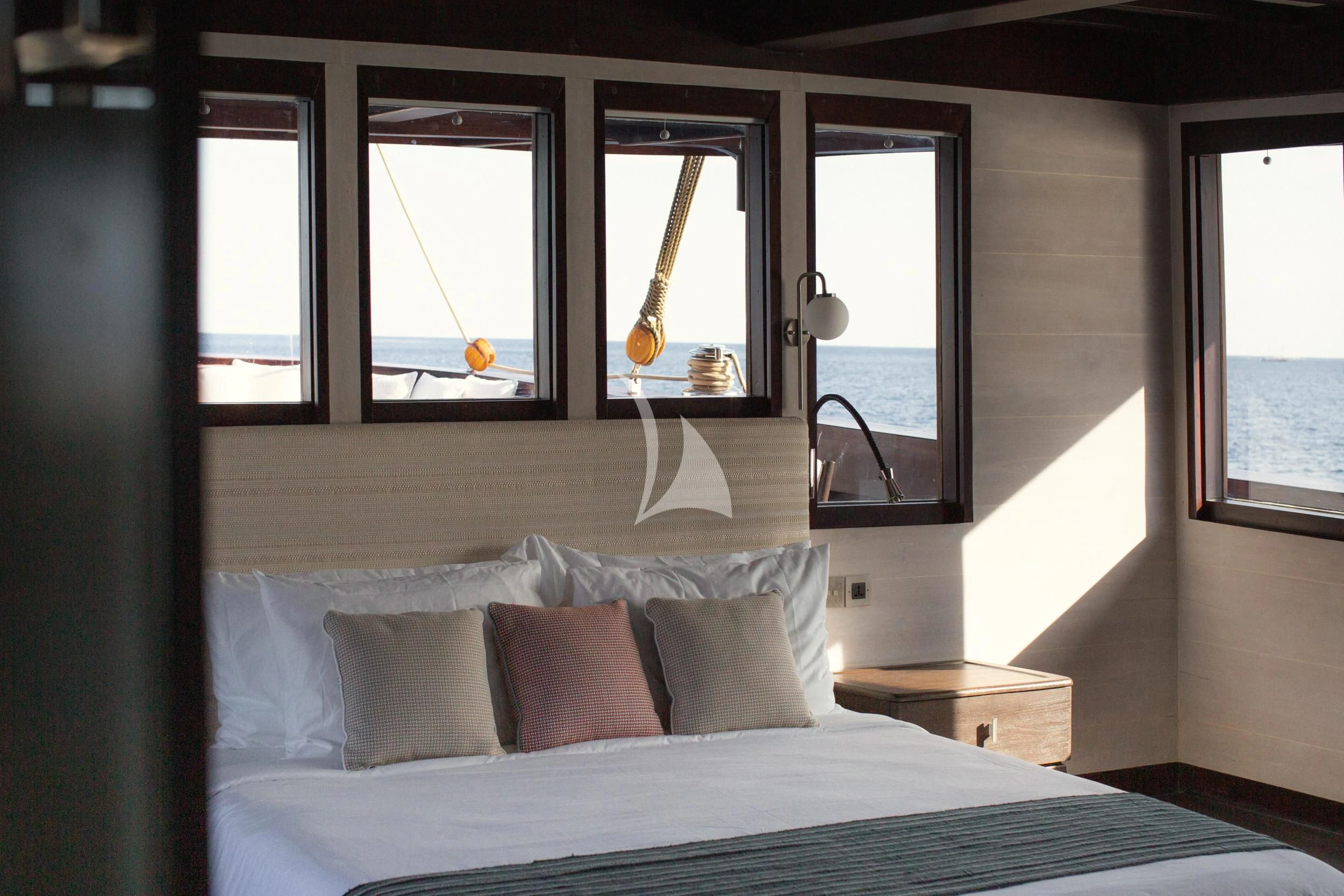 a bed with pillows and a window aboard VELA Yacht for Charter