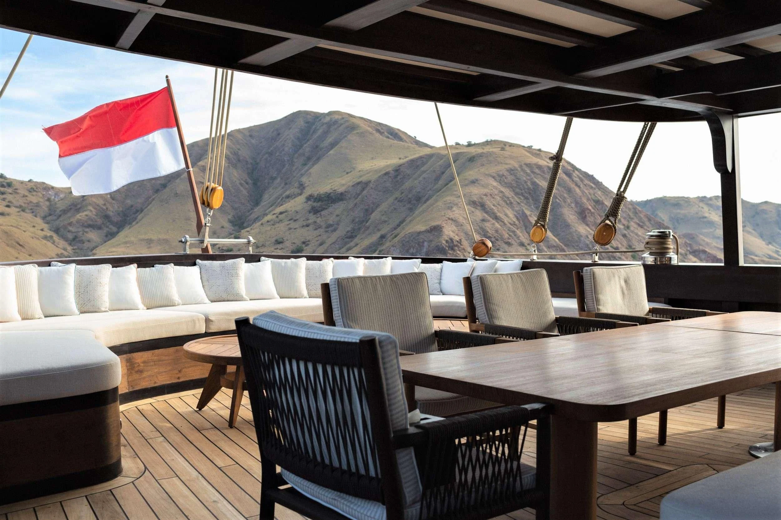 a deck with chairs and a flag aboard VELA Yacht for Charter